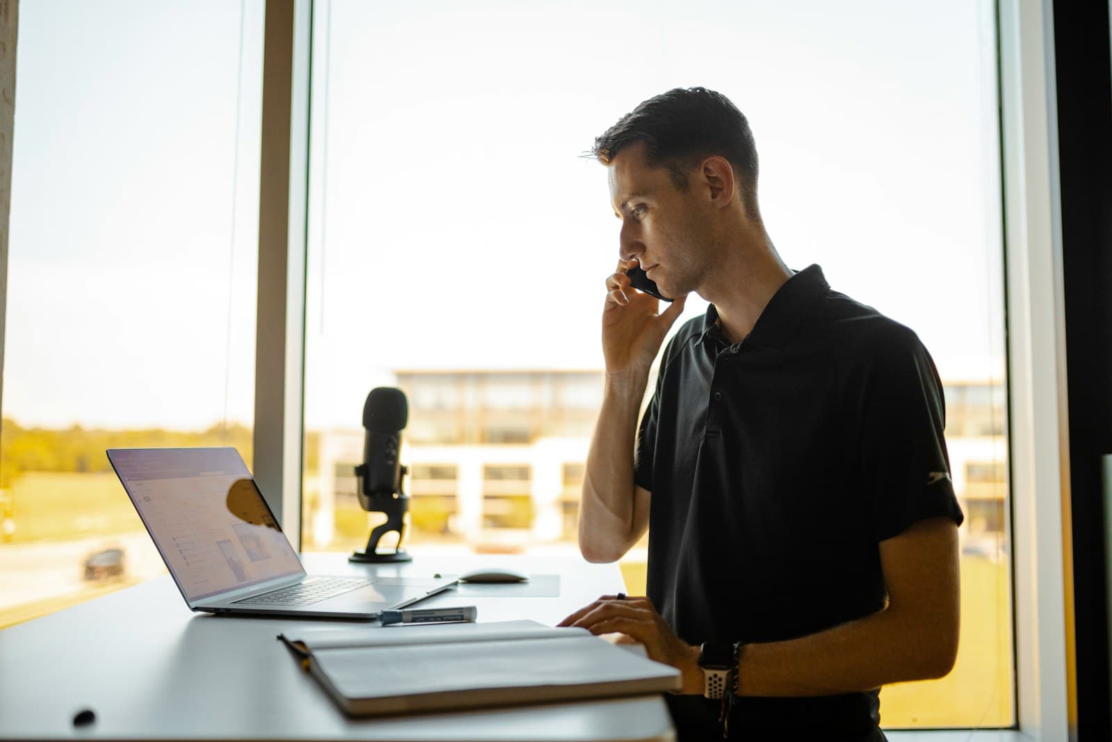 Contractor at his desk on the phone, working through leads from a laptop.
