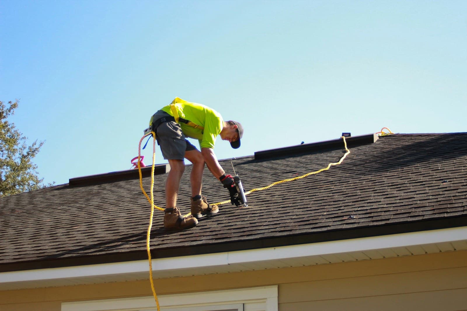 A roofer working with a power drill on a residential roof, the bread-and-butter Utah replacement job.